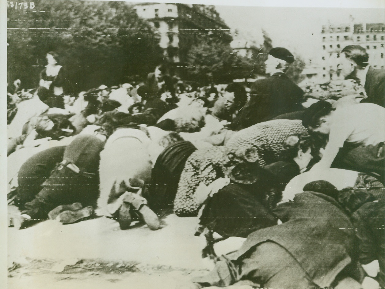 Everybody down, 8/28/1944. Paris—Civilians crouch low in the streets of panic-stricken Paris as sniper fire crackles overhead in the Place de L’Hotel de Ville. Terror reigned as gun shots rang out over the crowds watching the DeGaulle parade celebrating the liberation of Paris. Credit: ACME photo by Andrew Lopez for the War Picture Pool, transmitted via U.S. Signal Corps Radio Telephoto;