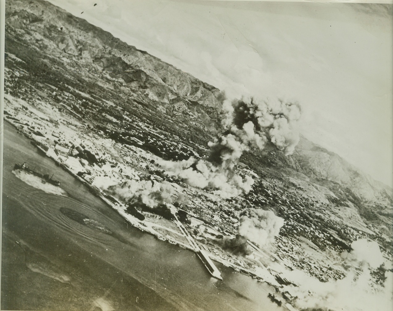 Yank Planes Return to Philippines, 9/24/1944. Cebu, Philippine Islands – Carrier planes from Admiral Halsey’s Third Fleet leave vast damage to enemy installations and shipping after weep over Cebu, vital Philippine harbor. In this action, 50 Jap planes were shot down in the air, 150 destroyed on the ground. Note near miss on ship at left. U.S. Navy Photo.  Credit: (ACME);