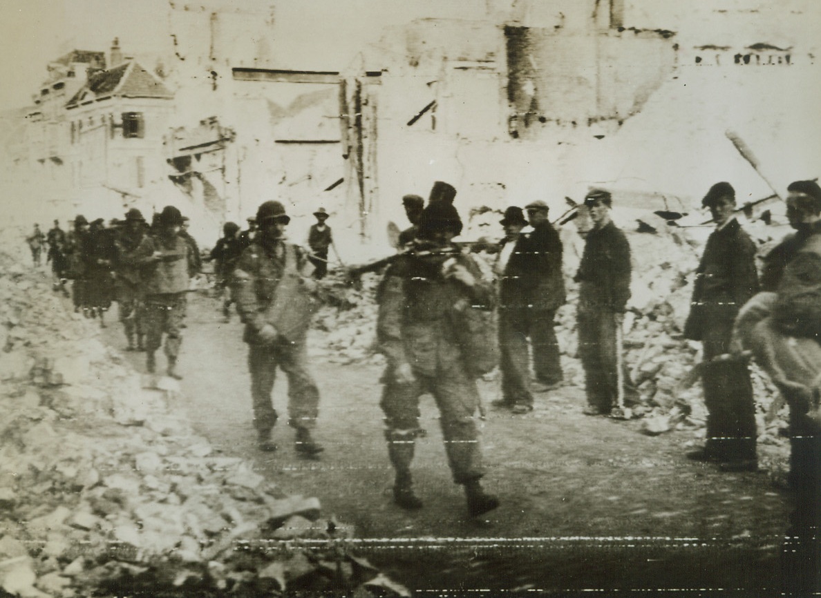 Yank Sky Warriors Return, 9/30/1944. NIJMEGEN, HOLLAND – Civilians stand aside as American paratroopers, returning from the front lines, march through the ruins lining this road in liberated Nijmegen.Credit (Army Radiotelephoto from Acme);