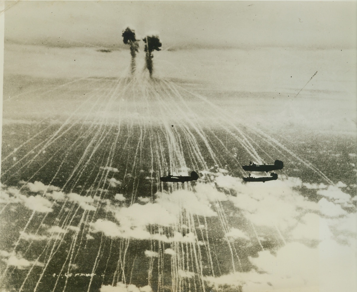 Jap Bombs Miss Liberators, 9/29/1944. A brace of Japanese phosphorus bombs burst over a formation of 7th Air Force Liberators winging over the Kazan Islands. The big American planes had just dropped their bombs on Iwo Jima, 650 miles from Tokyo, when Zeke fighters unloaded the phosphorus bombs and began a series of unsuccessful passes at the bombers. Credit: (U.S.A.A.F. Photo from ACME);