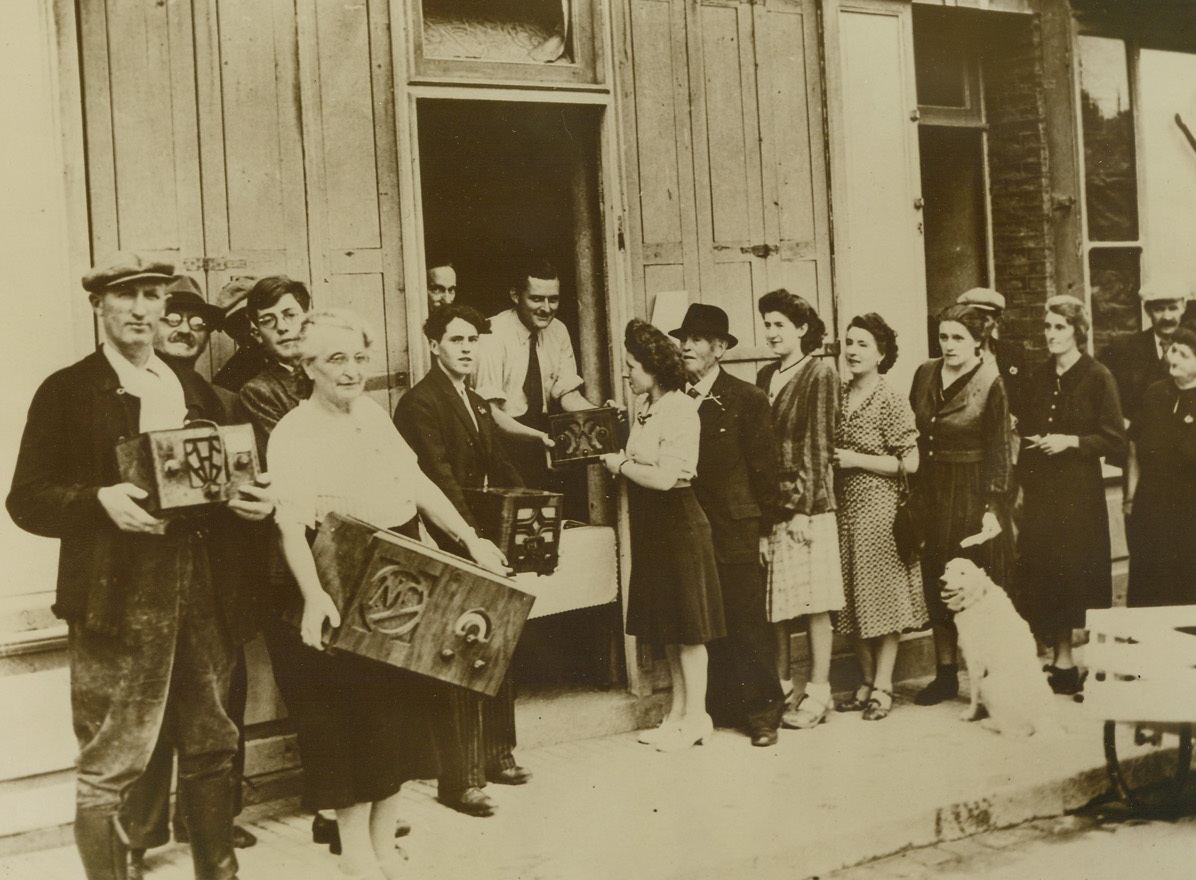 CONFISCATED RADIOS RETURNED, 9/5/1944. FRANCE—When the Germans were in the saddle in France, it was a crime punishable by death to listen to an allied broadcast.  Then, too, all radio sets were confiscated by the occupation authorities.  Here, at Villier Sur Mer, near the mouth of the Seine, residents reclaim their confiscated radios after liberation by the British.  Local French authorities broke into the German storehouse and distributed the sets to claimants who could establish proof of ownership.Credit: Acme;