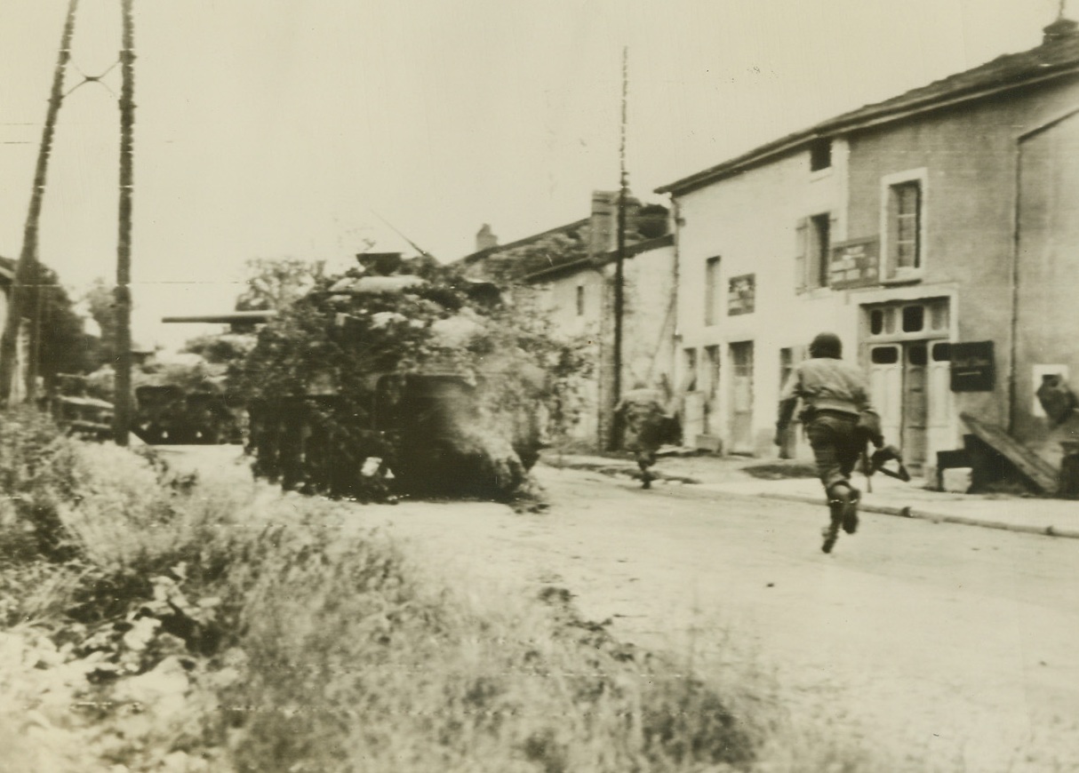 DUCK SNIPER FIRE, 9/7/1944. FRANCE—Infantrymen run for cover as German sniper fire breaks out from across the River Marne at Rachecourt. The camouflaged tank moves into position to protect bridge the Nazis tried to destroy.  Credit (Army Radiotelephoto from ACME);