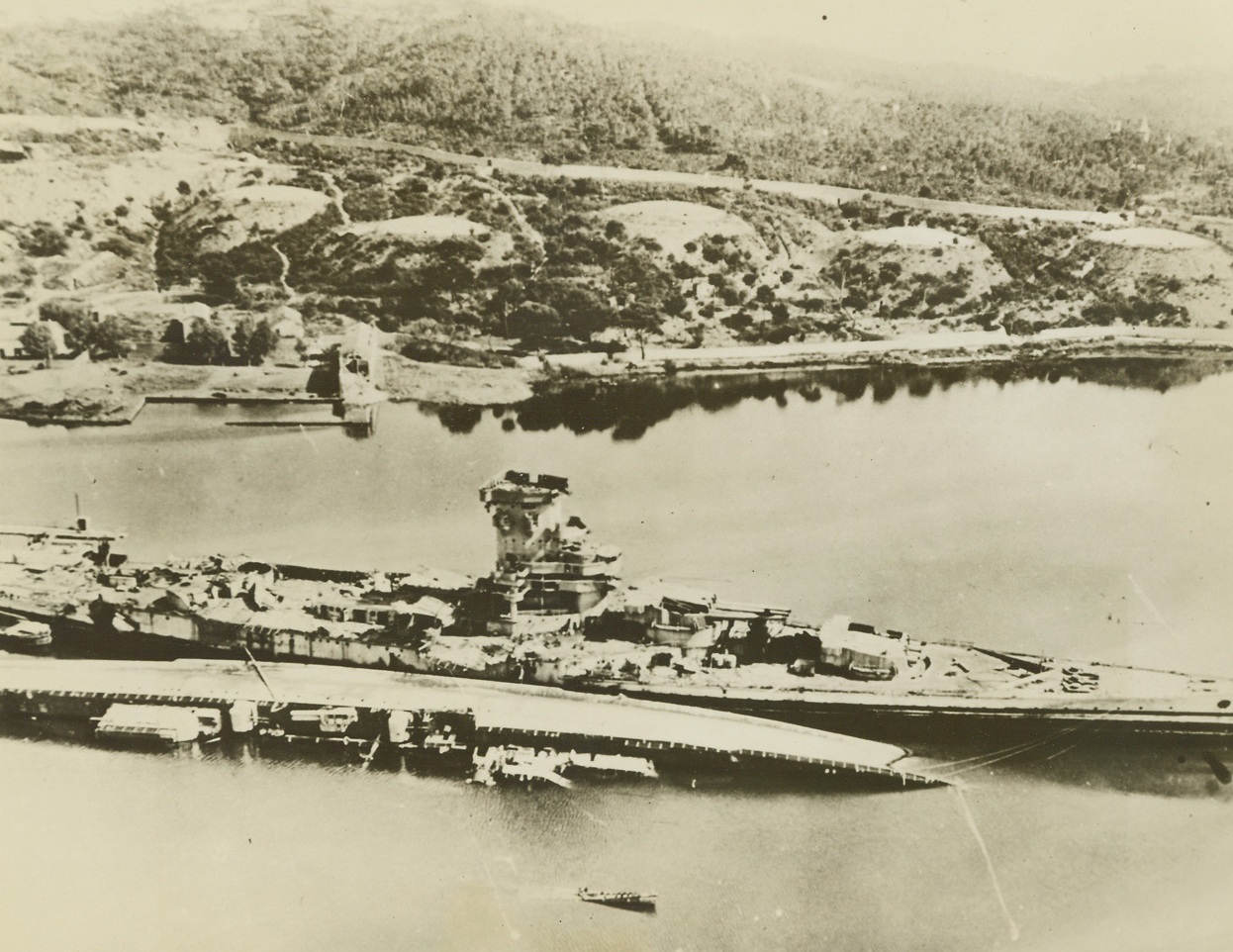 Battleship Strasbourg Silenced, 9/15/1944. France -- To silence the big guns of the former French battleship Strasbourg, which had been shelling forward elements from the invasion of southern France, bombers of the Mediterranean Allied Air Forces dropped a devastating concentration of bombs on the 702-foot vessel in the harbor of Toulon, causing many fires and explosions. The wrecked hulk of the ship is shown in the harbor near shore. In the foreground lies a capsized cruiser. Credit: USAAF photo from ACME;