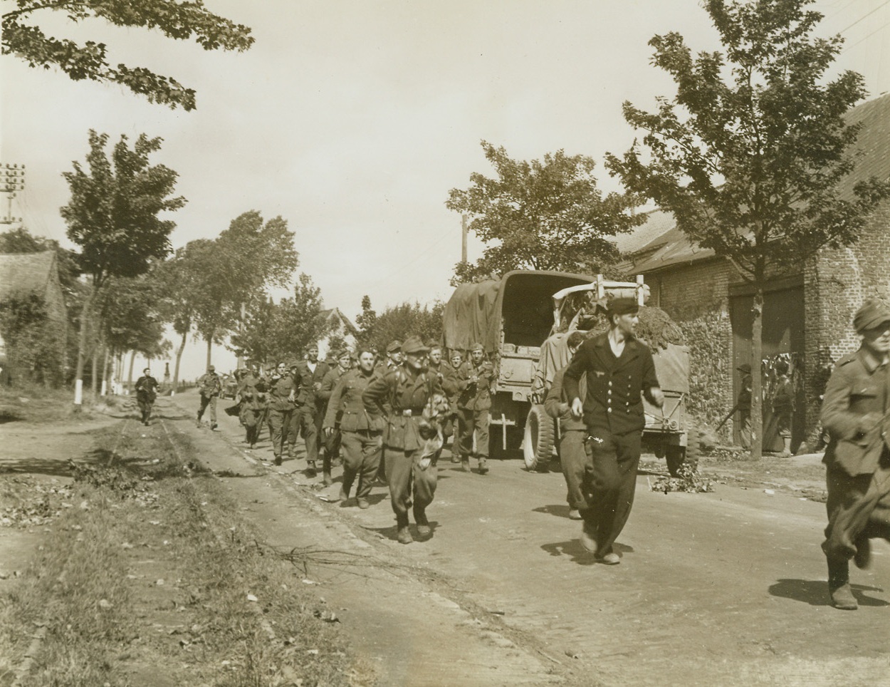 Nazis in a Hurry, 9/10/1944. Maubeuge, France -- Told to beat it on the double to the nearby prisoner of war cage, these Nazi captives obediently run down a road in liberated Maubeuge, on the Franco-Belgian border. All the fight knocked out of them, the Germans took flight at the command of their captors. Photo by Andy Lopez, photographer for the War Picture Pool. Credit: ACME;