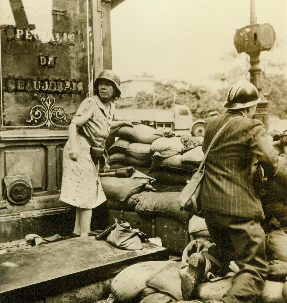 French Men And Women Fight For Beloved City, 9/8/1944. Paris -- After years of planning, members of the French Forces of the Interior rose as one to fight for Paris. Behind a sandbag barricade a helmeted French woman and man, both armed with weapons taken from the Germans, fight the hated Nazis in the streets of Paris. This picture, taken by an FFI photographer, was made during the week before Paris fell, when the French people were fighting to wrest their capital from the Germans without aid from Allied troops 9/8/44 (ACME);