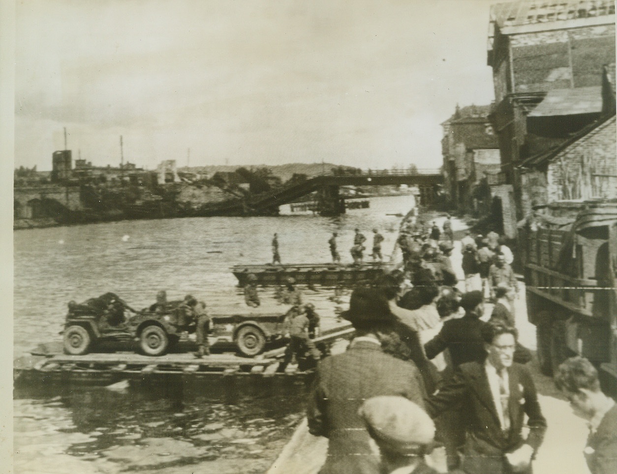 Jeeps Cross the Oise, 9/4/1944. COMPEIGNE, FRANCE -- Traveling on rafts, propelled by ropes from the opposite shore, American Jeeps cross the Oise River near Compeigne. In the background is the wreckage of the main bridge, which was destroyed by fleeing Nazis. Credit: (Army Radiotelephoto from ACME);