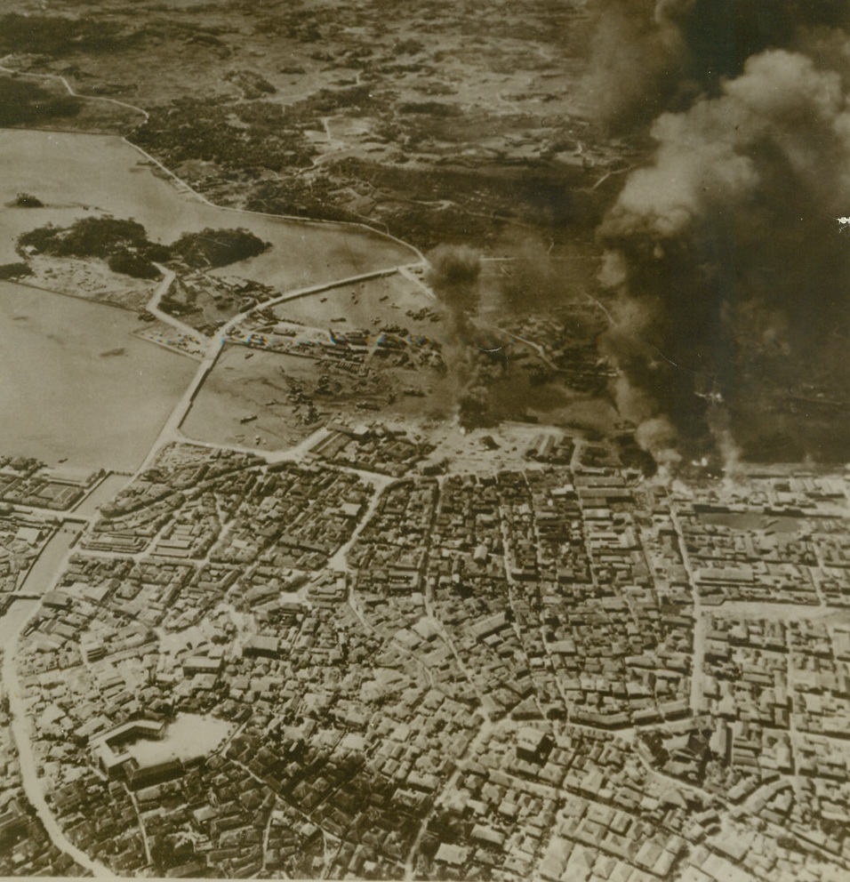 Marines On Okinawa Head for Naha, 4/1/1945. Okinawa – Infantrymen and Marines of the newly formed 10th Army were reported only eight miles from Naha, capital of Okinawa in the Ryukyu chain, after invasion of the island on April 1st.  Smoke towers into the sky from the dock area of the city after pre-invasion strike by Navy bombers. Credit (U.S. Navy photo from ACME);