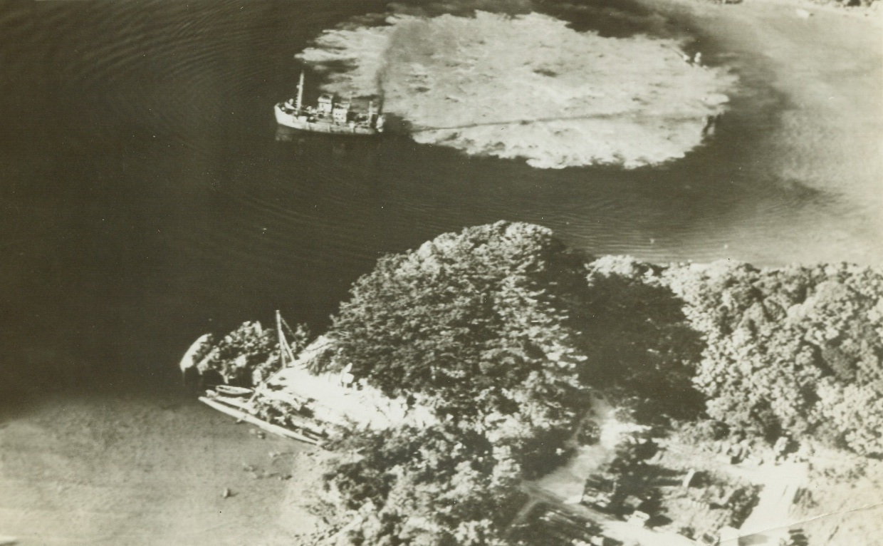 No Title. Hidden away in one of many sheltered coves of Okinawa is this Japanese midget submarine and torpedo boat base. Anchored in cove is Jap “Sea Truck”, narrowly missed by bomb from attacking carrier plane. Thousands of these small craft shuttle back and forth from Jap homeland to nearby island possessions carrying small quantities of military cargo. Midget sub is seen foreground and several torpedo boats, covered with palm leaf camouflage, are tied up at right angles. Yanks invading Keramo Retto discovered and destroyed 290 Jap “suicide” boats of secret fleet which apparently planned attack invading forces. Credit: U.S. Navy photo from ACME Telephoto;