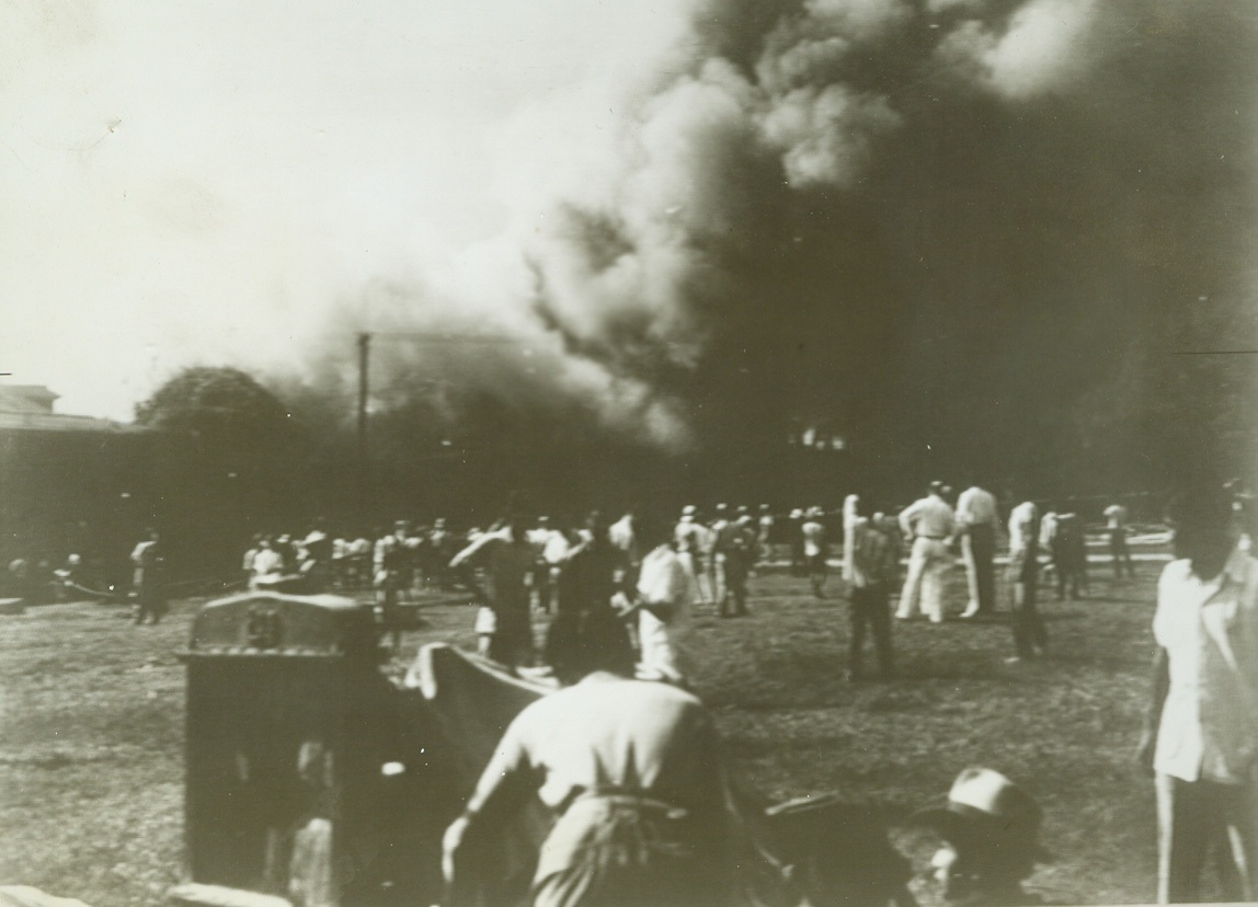 No Title. 115-smoke dims the sky as a building within Manila’s famed walled city burns after Jap air attack.No Credit line provided;