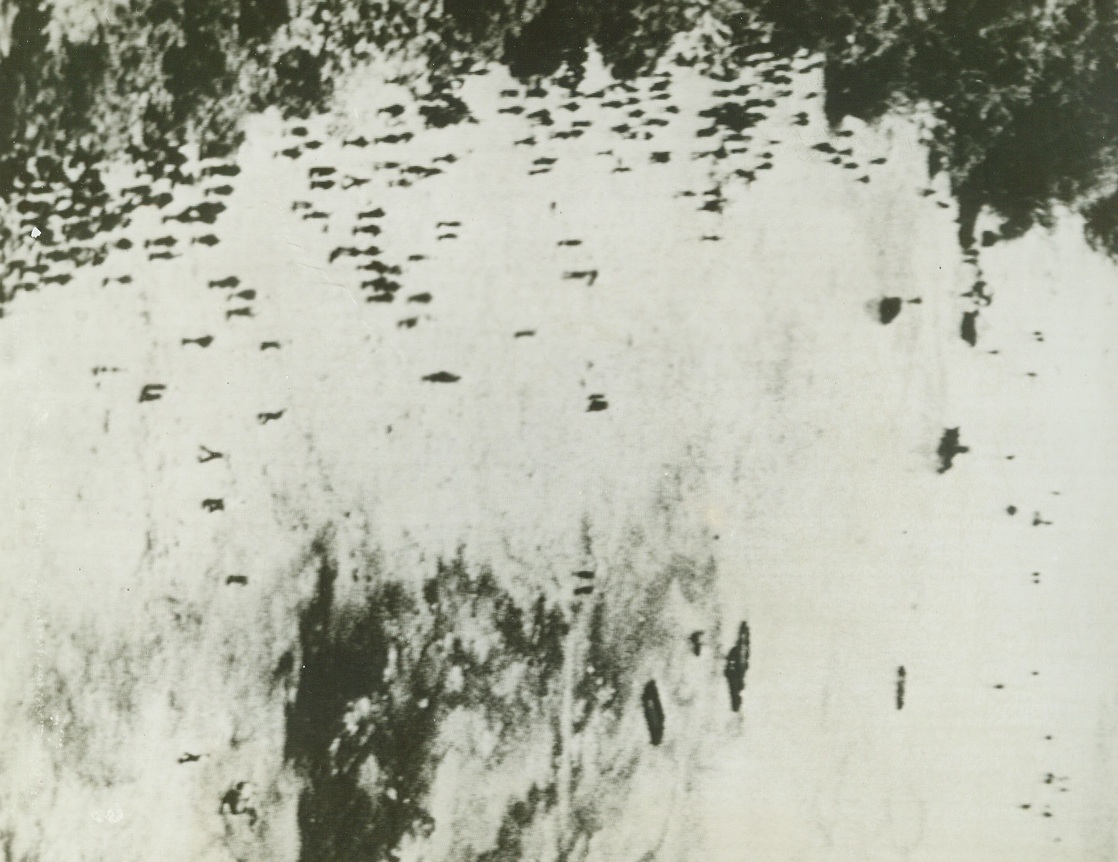 No Title. Men from the sunken U.S. Army transport, (formerly the S.S. President Coolidge) line the beach, while others wade ashore after their rescue by various types of naval units in the Solomon Islands area.  Credit: OFFICIAL NAVY NEWSREEL PIX.;