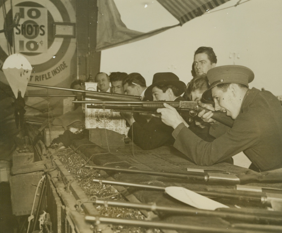 “Parachute Troops” Get the Works at “Coney Island.”, 6/30/1940  New York City—The latest innovation at Steeplechase Park, Coney Island, is a shooting gallery in which the targets are “Parachute Troops.” Pleasure seekers at the resort prefer these targets to the conventional floating ducks and similar targets. The “jumpers” float down from the ceiling of the gallery and are popped at as they descend. One of the much perforated targets is seen floating down while would-be marksmen shoot at others. Credit: ACME.;