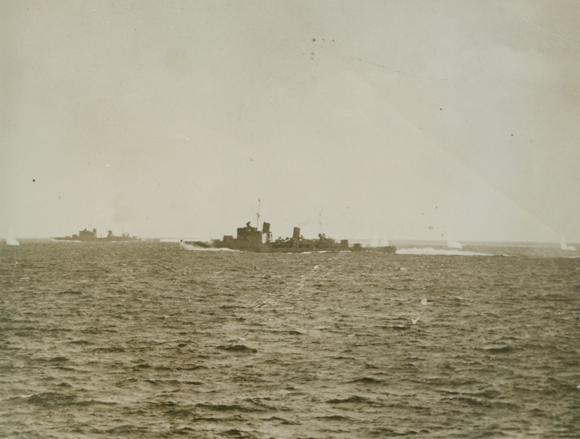 SHELLS FALL AROUND BRITISH SHIPS IN NAVAL BATTLE, 1/14/41  OFF THE COAST OF SARDINIA—Shells from distant Italian warships raise geysers around two of the British cruisers which took part in the naval engagement westward of Sardinia on Nov. 27th. The battle took place after British planes located an Italian force of two battleships and a large number of cruisers and destroyers about 75 miles away from the British flotilla. The British ships changed course and sped to intercept the enemy. This picture was taken from one of the units of the British fleet during the long range engagement which ended with the Italian ships seeking the protection of coastal defenses. Credit: Acme;