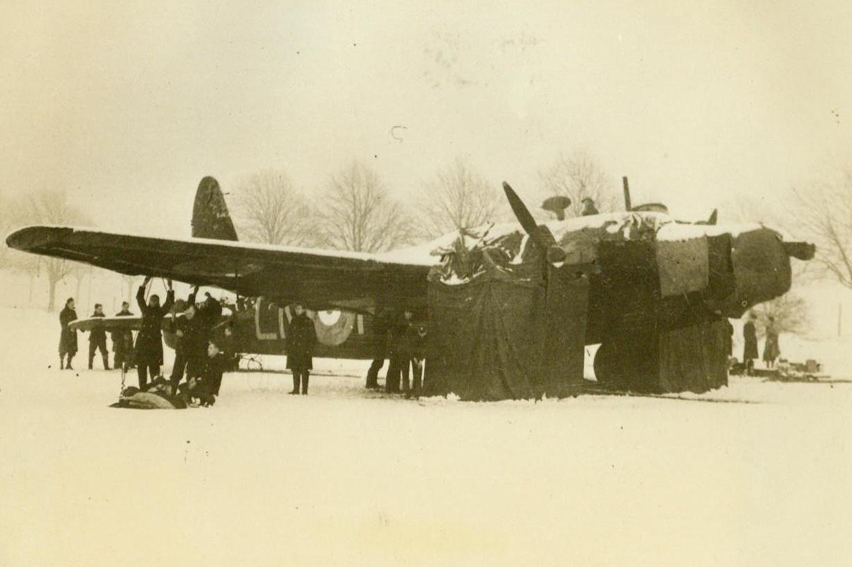 Britishers Fight Winter to Keep Bombers Ready, 2/5/41  Somewhere in England -- A ground crew works to get a British bomber ready for flight during the recent spell of snow and bitter cold which swept the country. Six aircraftsmen, headed by a corporal, are responsible for the upkeep of each of the bombers of the British Bomber Command. Passed by British censor. Credit: ACME;