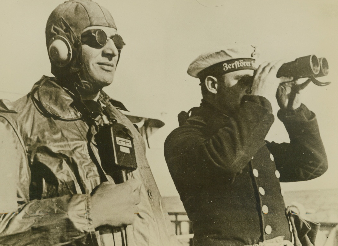 GERMAN DESTROYER ON PATROL DUTY IN NORTH SEA, 11/13/1939. GERMANY—According to German sources this picture was made aboard a German destroyer on patrol duty in the North Sea. As one officer scans the horizon for signs of smoke from foreign vessels, the other officer stands ready with microphone and earphones to communicate with the engine room. Credit: Acme;